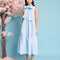 model wearing baby blue tiered midi dress with exaggerated bow neckline 