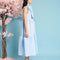 side view of model wearing baby blue tiered midi dress with exaggerated bow neckline
