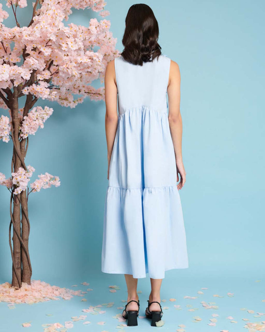 back view of model wearing baby blue tiered midi dress with exaggerated bow neckline