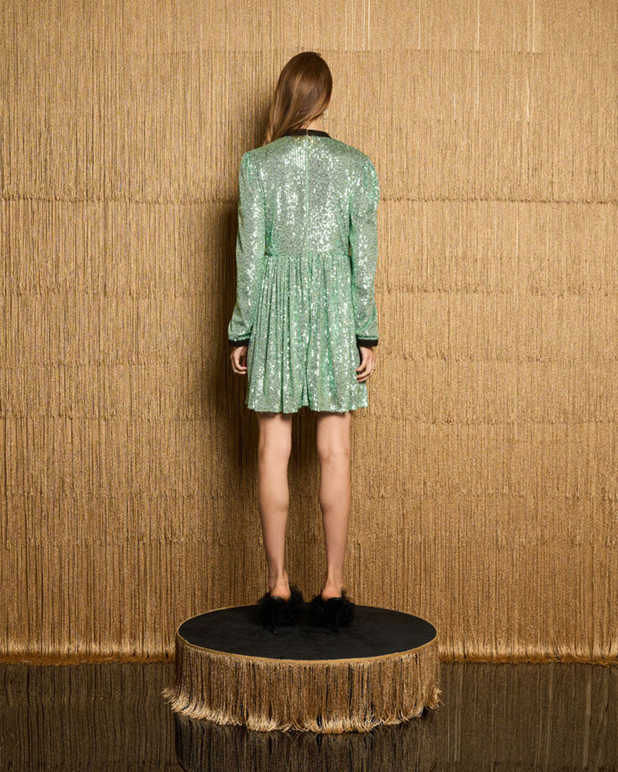 back view of model wearing green sequin mini dress with black beaded bow front