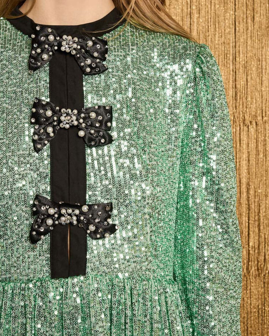 up close of model wearing green sequin mini dress with black beaded bow front