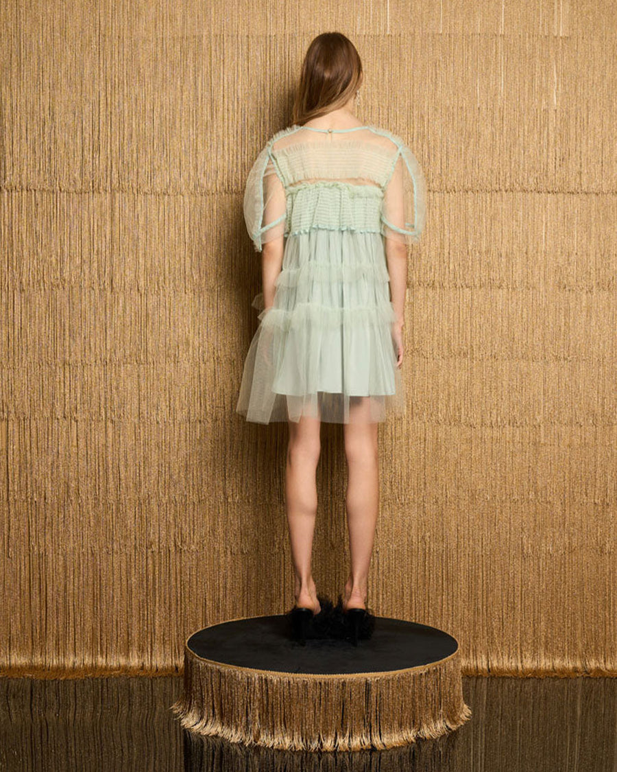 back view of model wearing light green mini dress with pretty sea green tulle tiers