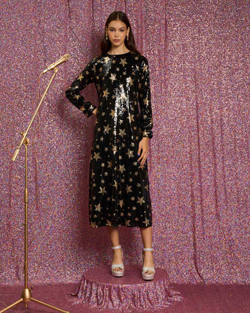 model wearing black sequin midi dress with long sleeve and gold star print