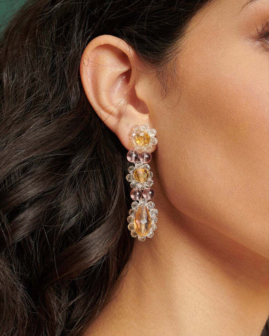 up close of model wearing beaded white and yellow flower dangle earrings