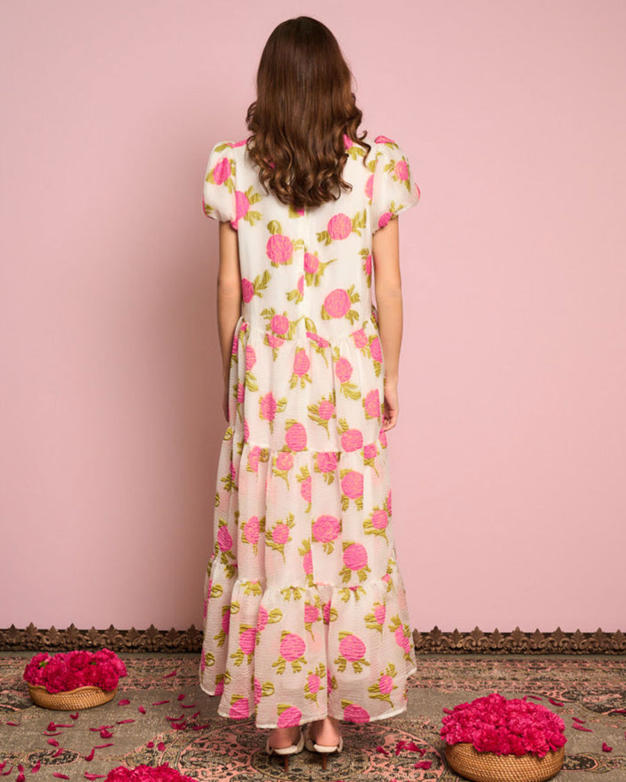 back view of model wearing white maxi dress with puff sleeves, tiered skirt and all over pink rose print
