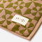 up close of muted pink and olive green geometric floral bath mat