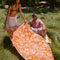 model laying orange and pink abstract palm tree and sun design woven towel