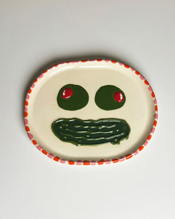 handmade tray with olive eyes and dill pickle smiley face with pink and red trim