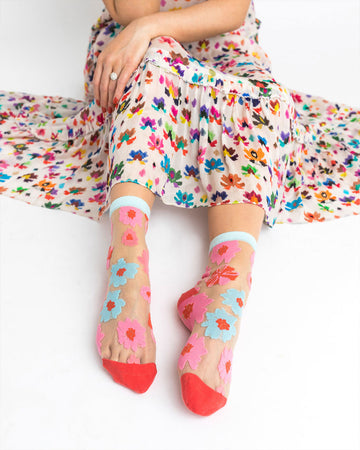 model wearing sheer socks with blue and pink flowers with light blue and red trim
