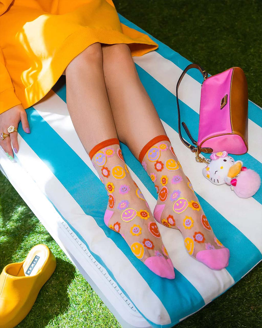model wearing sheer socks with colorful smiley face and smiley floral print
