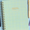 green grid notebook with gold foil 'professional procrastinator' across the front on a blue background