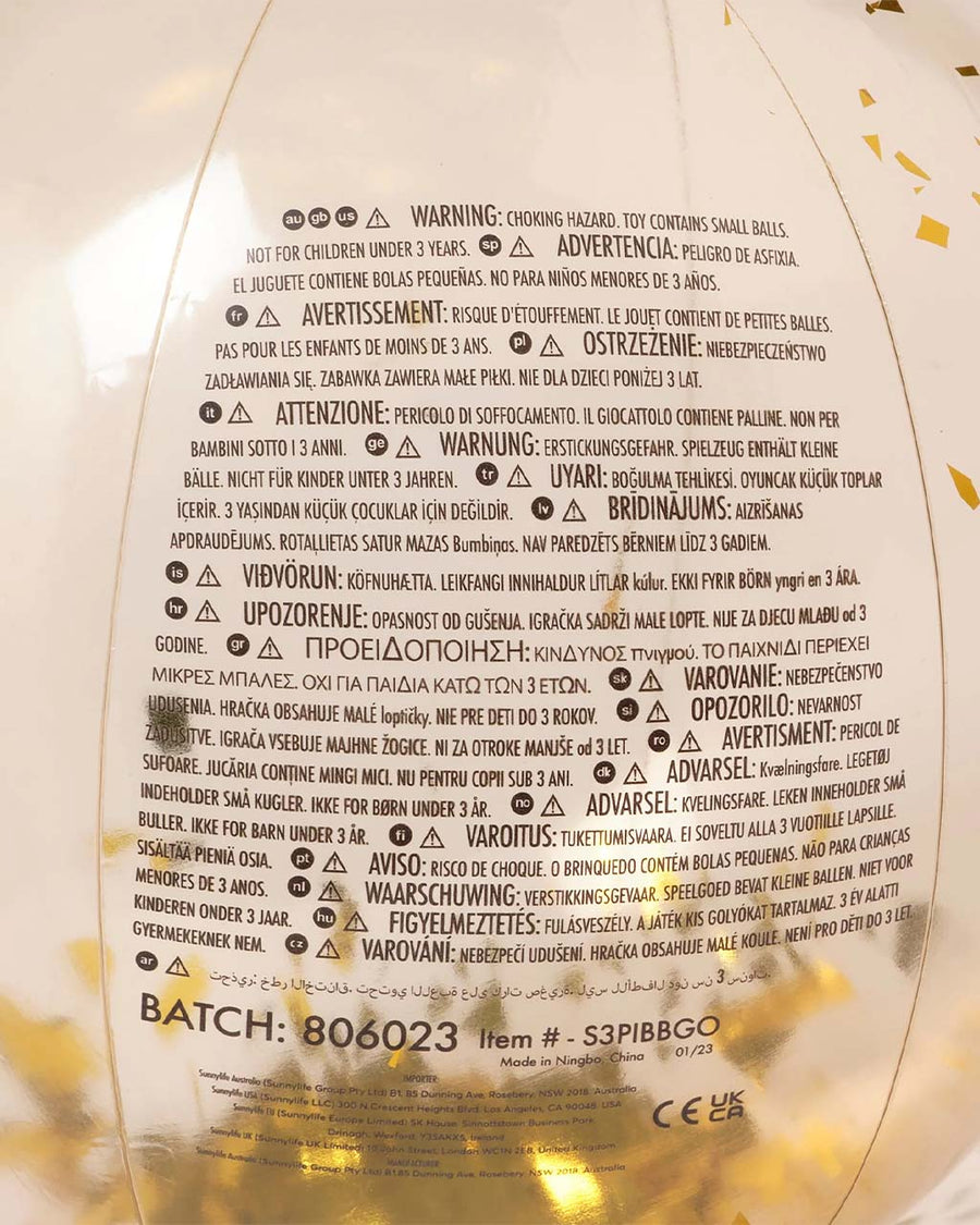 choking hazard warning label on cream clear beach ball with gold flakes inside
