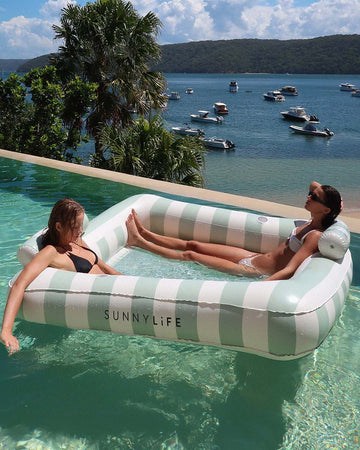models floating in oversized mint and white stripe float for two people