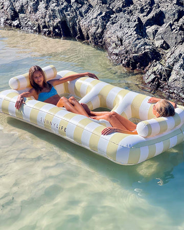 models floating on oversized pastel yellow and white stripe float for two people