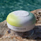 yellow, white and green circular waterproof speaker on a rock