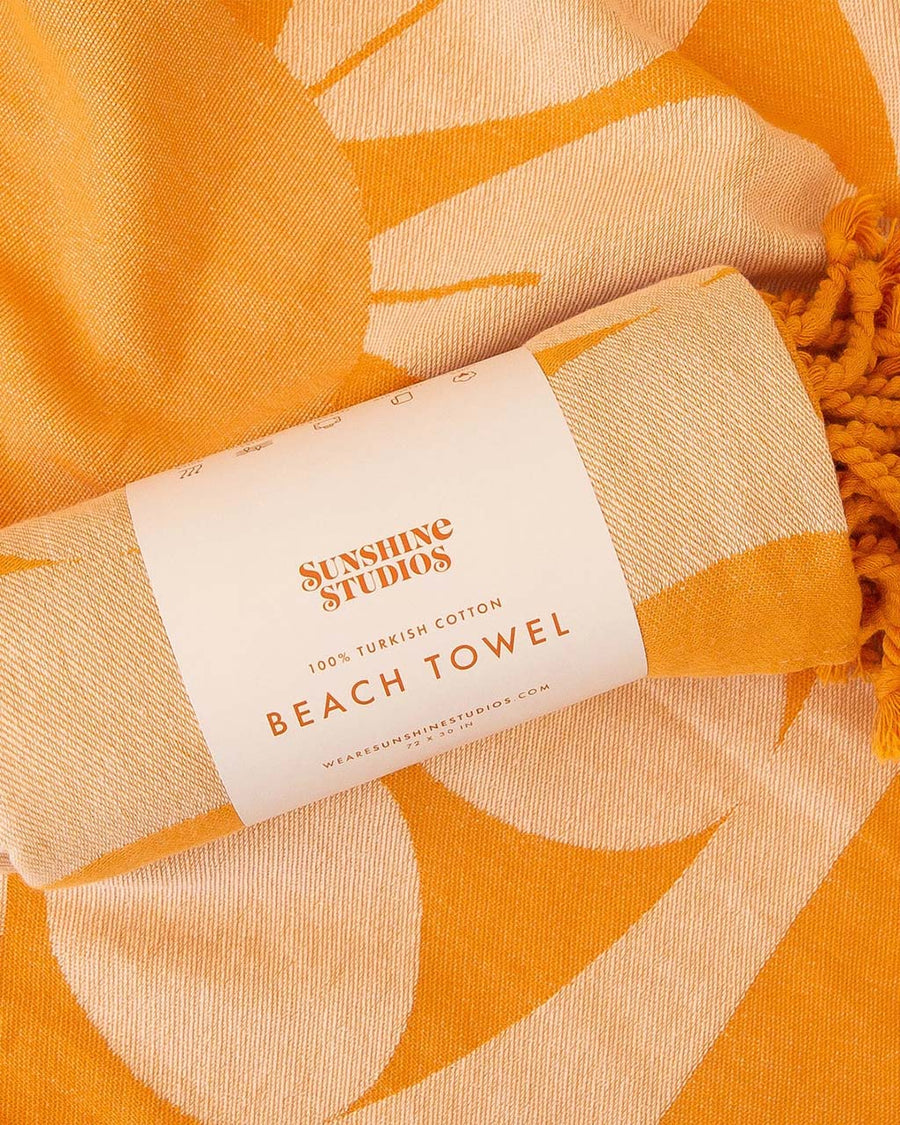 packaged orange and white retro flower towel with tassels on the end