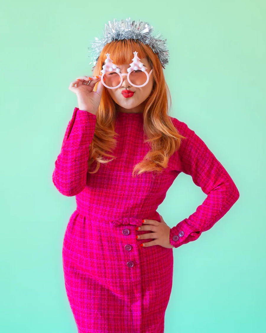 model wearing pink pastel sunglasses with pink lens and pink tree with pom details on top