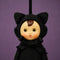 up close of cute plush dressed as a black cat and has a vintage circle face