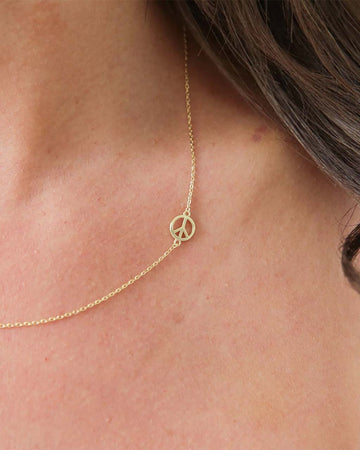model wearing gold peace sign necklace