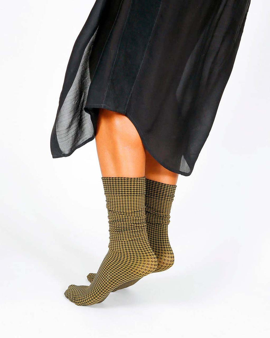side view of model wearing green and black houndstooth high crew socks