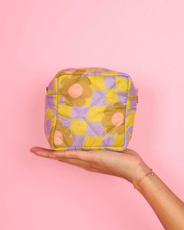 model holding yellow and purple trippy checker floral puffy square pouch