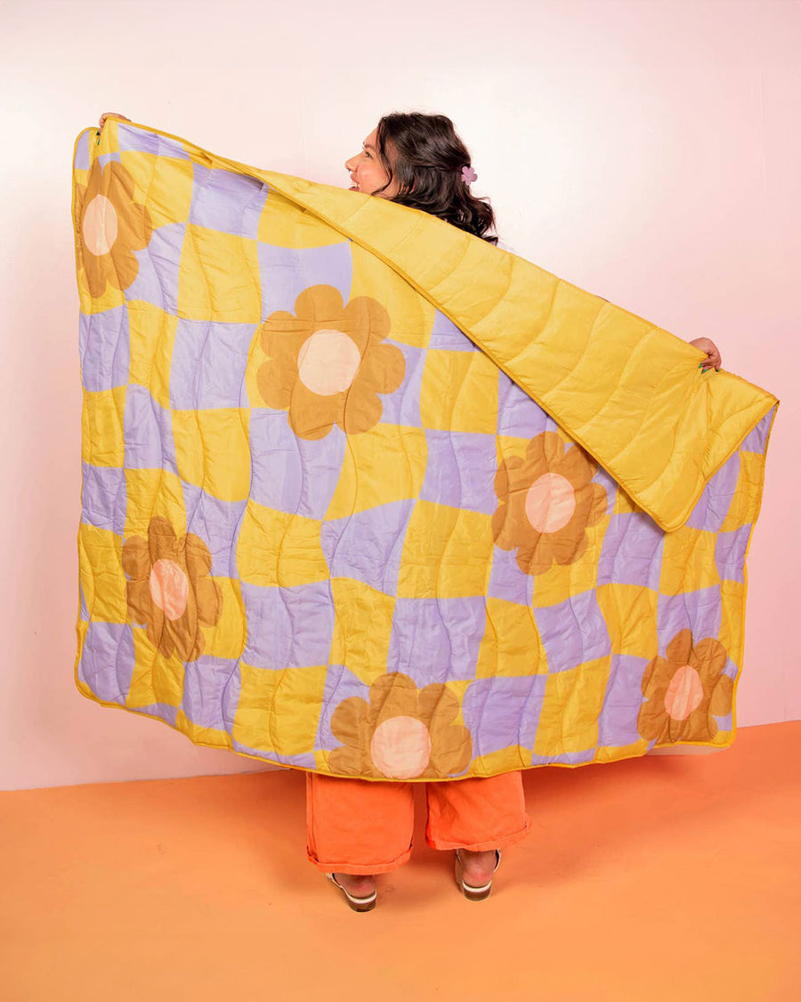 model holding lime and purple trippy checker with bold flower puffy blanket