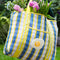 model carrying blue, white and yellow plaid large recycled plastic tote bag with ric rac detail and egg patch on the front pocket with flowers inside