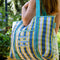 model carrying blue, white and yellow plaid large recycled plastic tote bag with ric rac detail and  embroidered three fishies on the front pocket