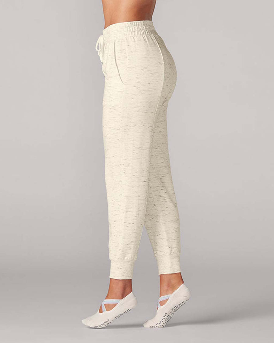 side view of model wearing cream jogger pants with grey speckles