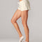 side view of model wearing cream shorts with elastic waist, drawstring and all over grey speckles