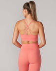 back view of model wearing bright coral sports bra