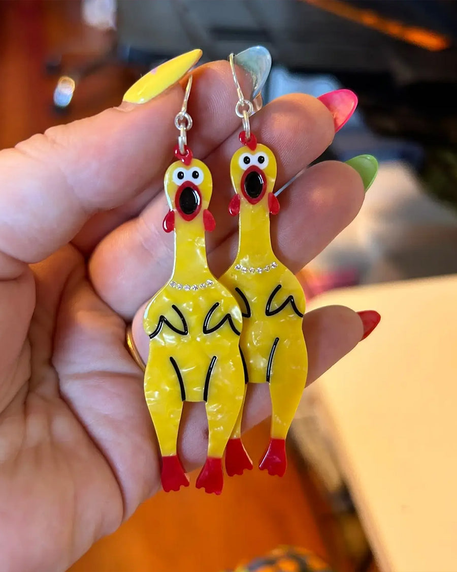 model holding yellow rubber chicken dangle earrings