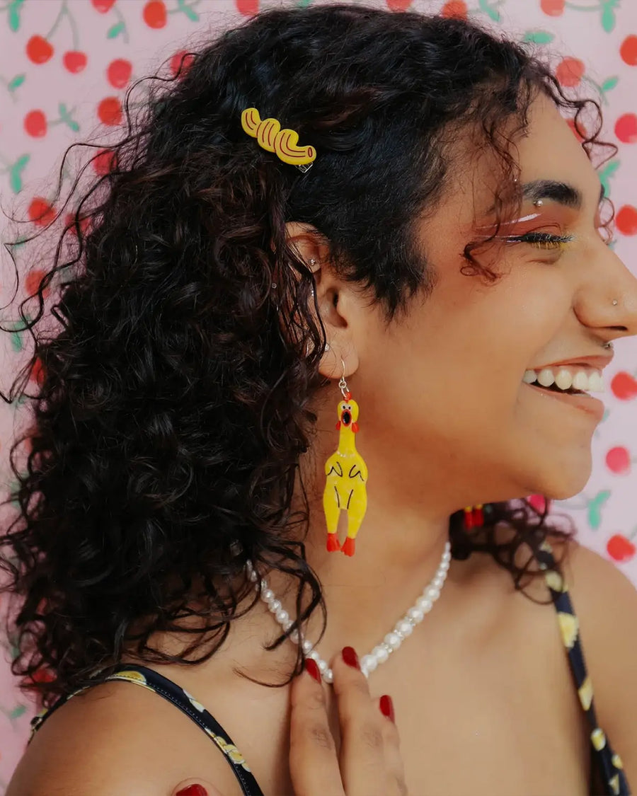model wearing yellow rubber chicken dangle earrings