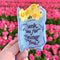model holding light blue 'plastic bag' hair claw with 'thank you for being you' across the front and yellow daffodils coming from the top