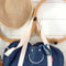 denim duffle bag with white smiley face and white straps hanging on hook