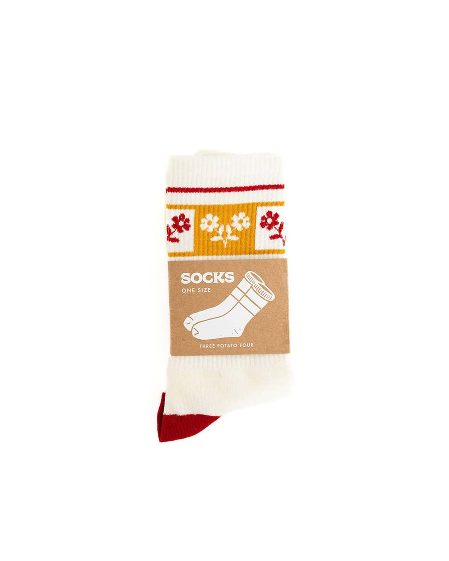 front view of white crew socks with yellow and red floral print across the top and red heel