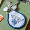 blue moomin smelling flowers with moomin charm on a green book