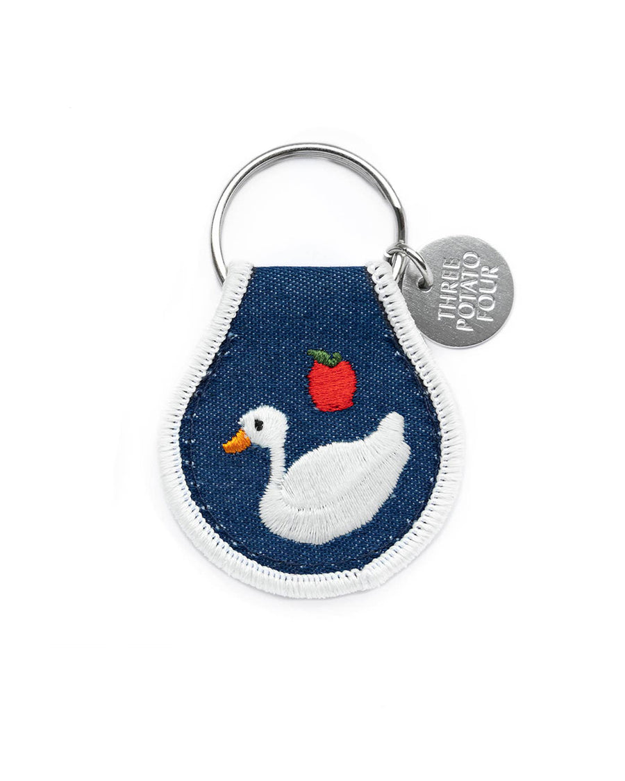 flipside of denim colored patch keychain with white embroidered sitting goose, apple and white trim