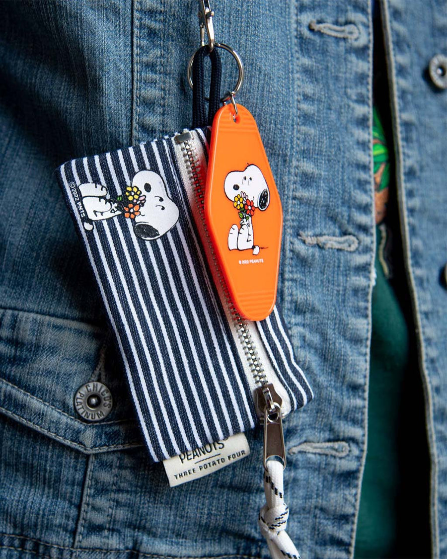 model wearing orange key tag with snoopy holding a flower bouquet graphic