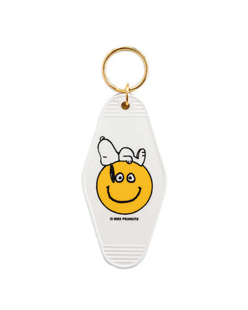 white key tag with snoopy laying on a yellow smiley face graphic