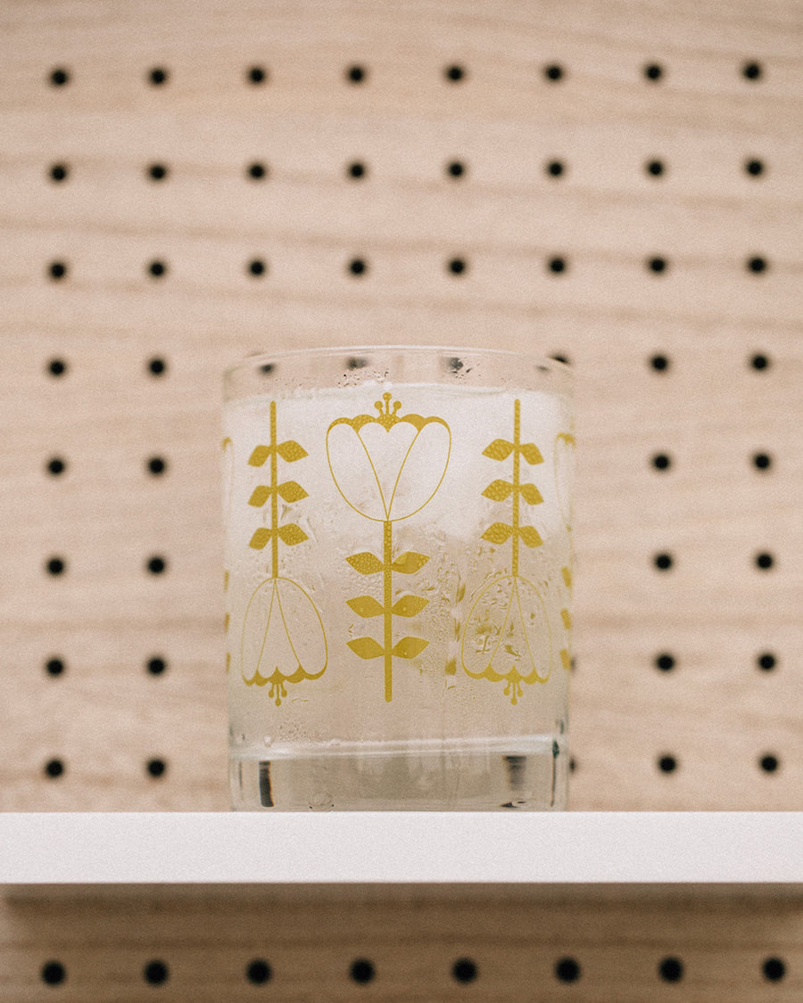clear glass with olive green tulip print on a shelf