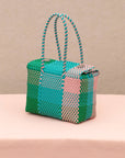 side view of teal, pink, and green woven handbag