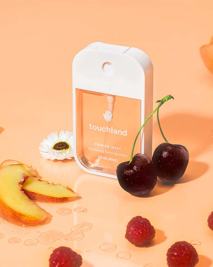 velvet peach hand sanitizer surrounded by cherries, peach slices and raspberries 