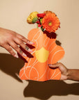 model holding orange flower paper vase