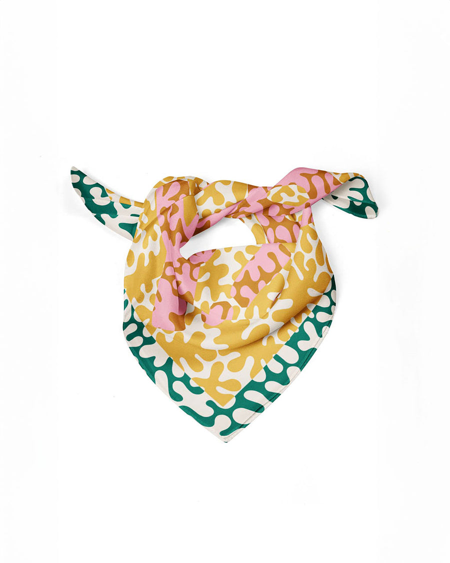 yellow, pink and green blob fabric wrap with the JOY! across the front tied as a kerchief