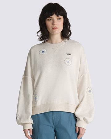 model wearing cream sweatshirt with all over blue flower appliques, blousant sleeves, and black vans logo