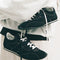 model carrying black vans super low pro trainer sneakers  with white laces