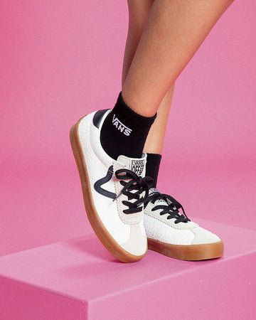 model wearing white sports low sneaker with black and cream details