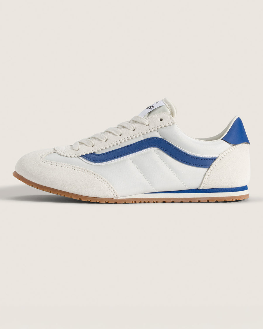 side view of white vans super low pro sneaker with royal blue trim and iconic stripe