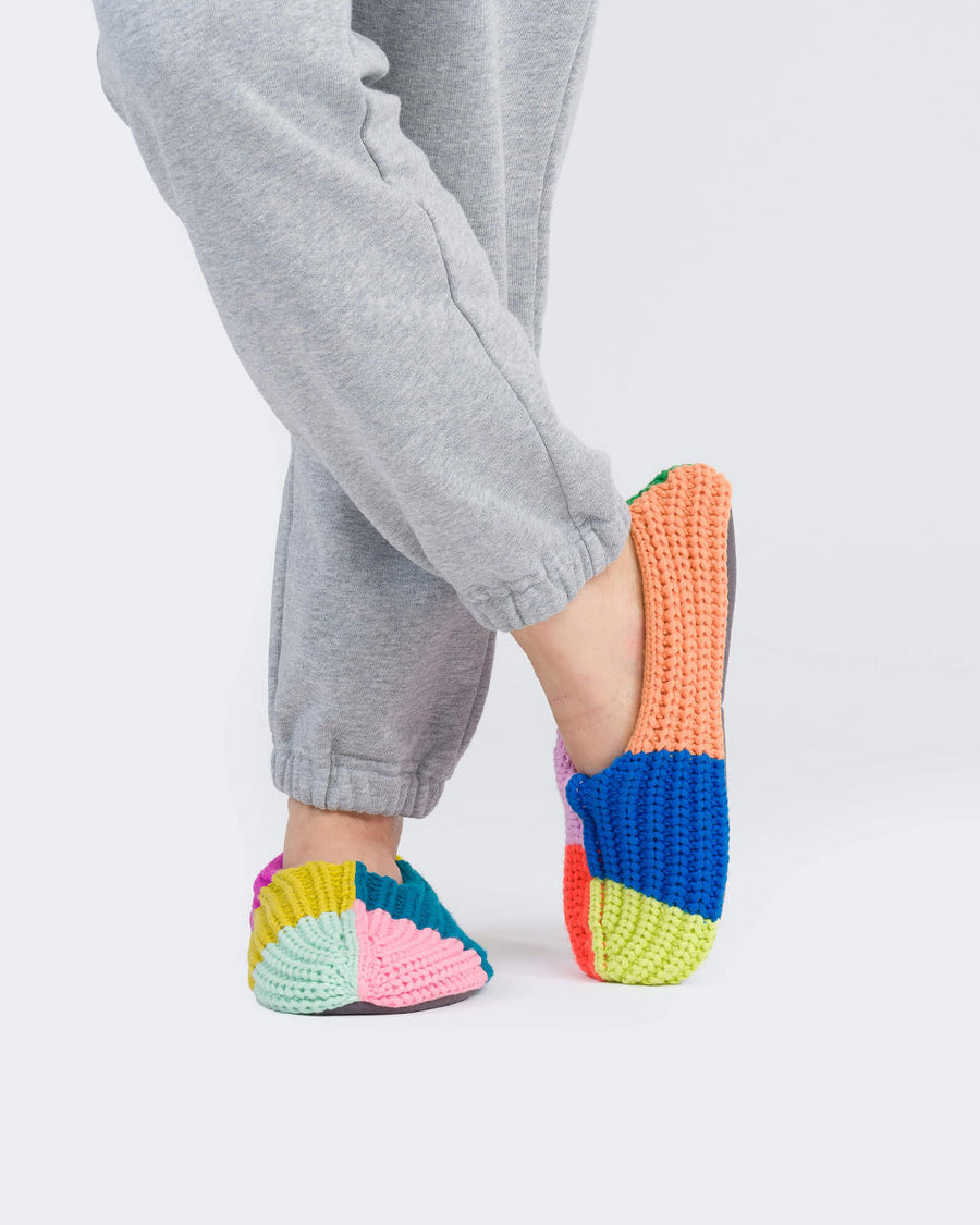 model wearing mismatched slippers with fuzzy interior with their legs crossed